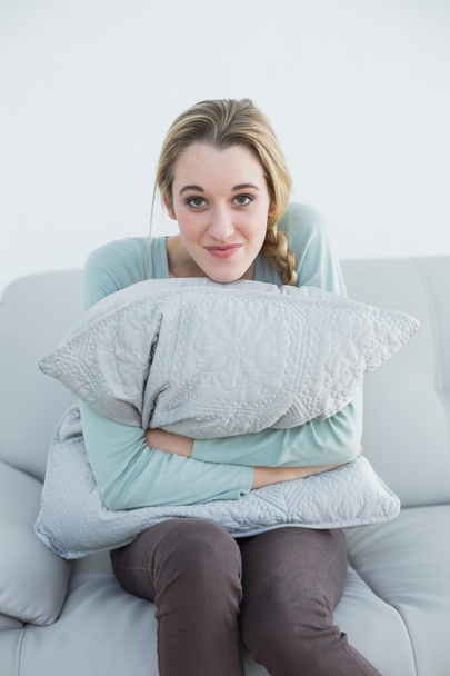 Gorgeous smiling woman cuddling with pillow sitting on couch - Foto, immagini