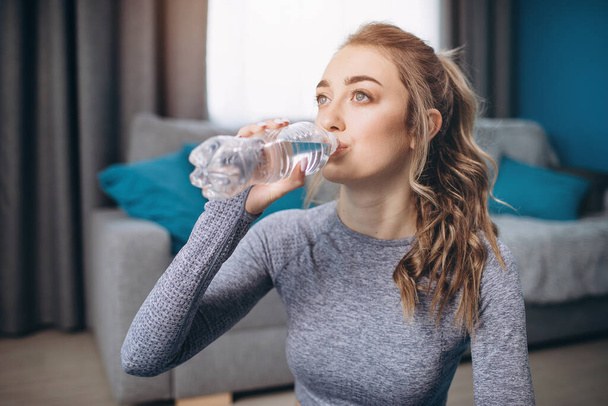 Портрет очаровательной девушки, пьющей воду после тренировки
 - Фото, изображение