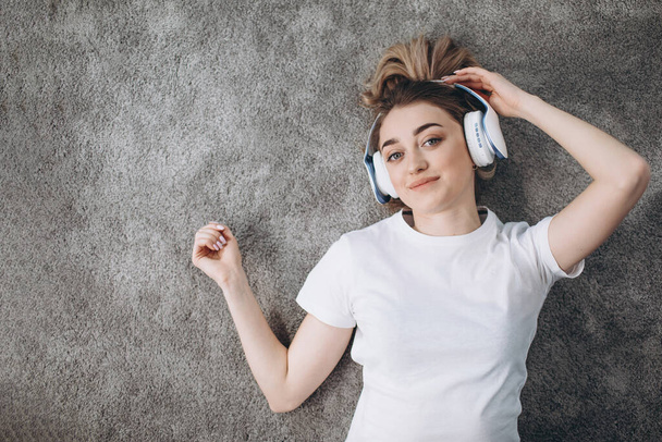Top kilátás fitness lány pihentető szőnyegen fülhallgató - Fotó, kép