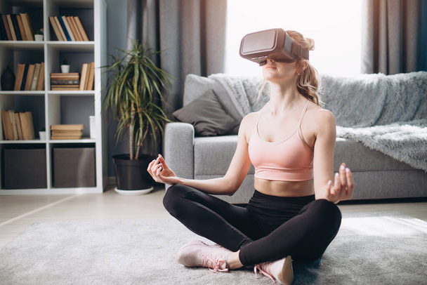 Young girl meditating at home in virtual glasses - Foto, afbeelding