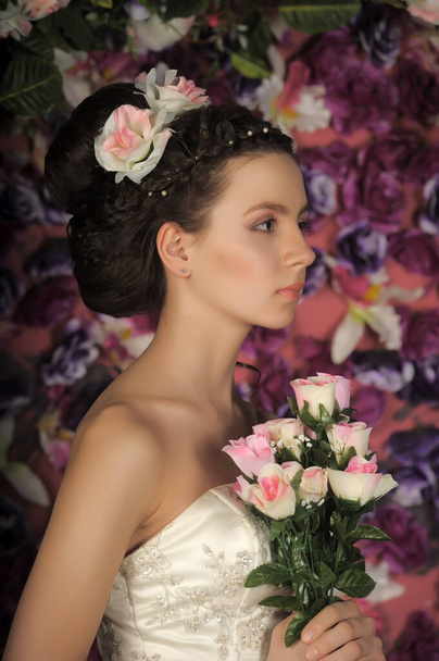 Young bride with flowers in her hair on a floral background - Фото, изображение