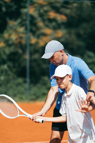 Tennis instructor with young boy in tennis training lesson - Fotoğraf, Görsel