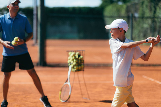 Instrutor de tênis com menino tendo uma lição de tênis em Clay Court
. - Foto, Imagem