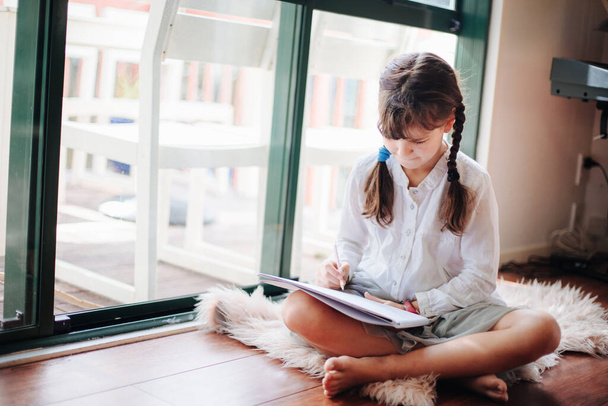 portrait intérieur de jeune fille écrivant à la maison près de la fenêtre
 - Photo, image