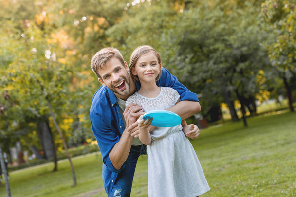 Close up portrait of happy smiling father hugging his smiling pretty daughter outdoor - Foto, Imagem