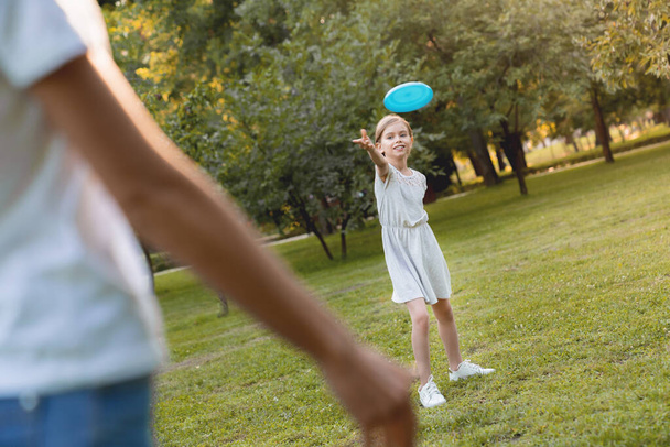 Little cute girl throwing to her mother frisby and having fun outdoors - Foto, Imagem