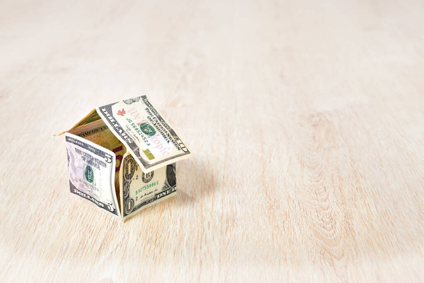 Geld huis gemaakt van dollarbiljetten op houten achtergrond - Foto, afbeelding