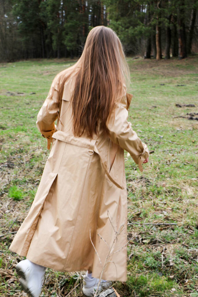 beautiful girl, blonde with long hair, walks in the spring near the forest in a brown coat., serenity and freedom - Fotoğraf, Görsel