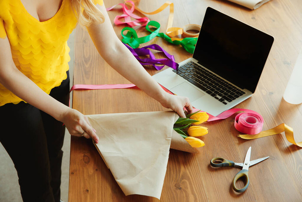 Kwiaciarnia w pracy: kobieta pokazuje, jak zrobić bukiet z tulipanami, pracy w domu koncepcji, przy użyciu papieru pokrycia - Zdjęcie, obraz