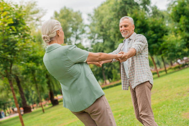 Loving senior couple holding hands and enjoying a romantic day at the park - Фото, изображение