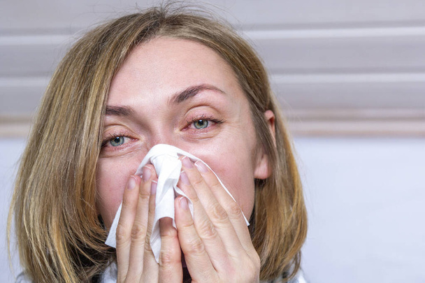 Retrato de una mujer enferma estornudando, tosiendo, sonándose la nariz en pañuelo sobre fondo claro, de cerca. Enfermedades conceptuales del virus de la gripe, resfriados, alergias estacionales, coronavirus
 - Foto, imagen