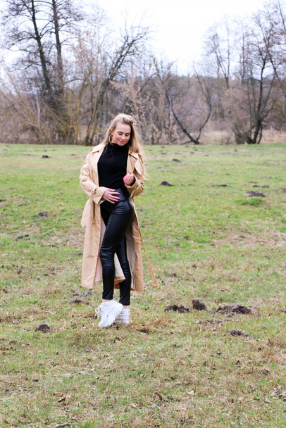 beautiful girl, blonde with long hair, walks in the spring near the forest in a brown coat., serenity and freedom - Fotografie, Obrázek