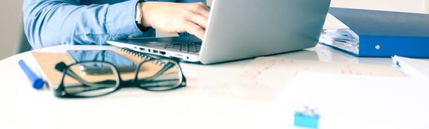 Bureau blanc avec carnet de notes, lunettes, téléphone portable, ordinateur et une main dactylographiée. Homme travaillant à la maison
. - Photo, image