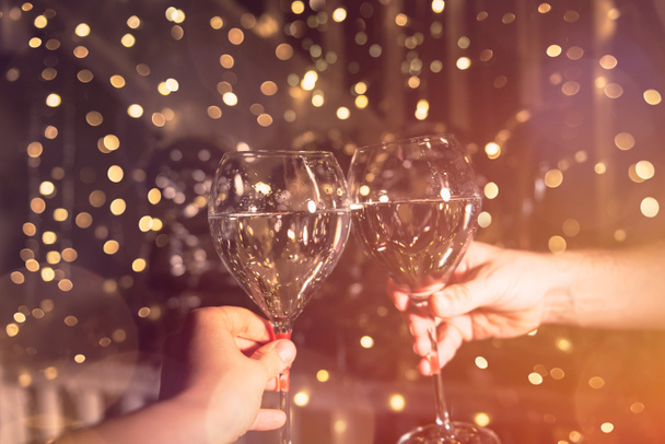 ¡Salud! Jovencita y un hombre están animando con champán en las copas para la celebración de Año Nuevo. Hermosas luces de Navidad en el fondo
 - Foto, Imagen