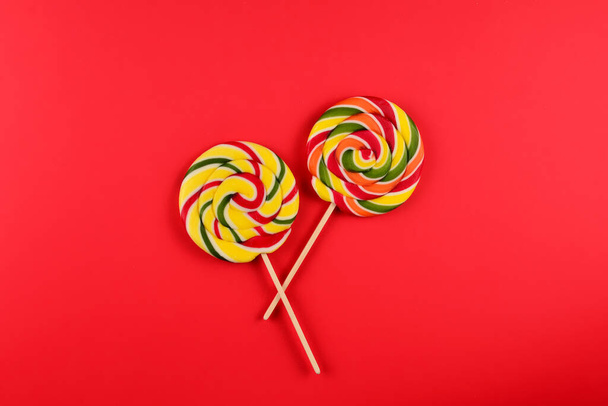 Colorful candy on a red  background. Lollipop. Top view. Copy space. - 写真・画像