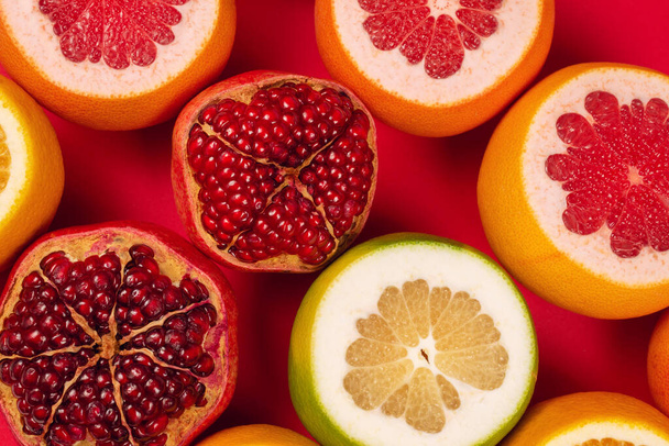 Juicy grapefruit, orange, pomegranate, citrus sweetie on red background.  - Foto, Bild