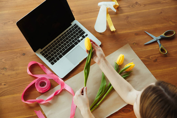 Florist at work: woman shows how to make bouquet with tulips, working at home concept, top view - Fotoğraf, Görsel