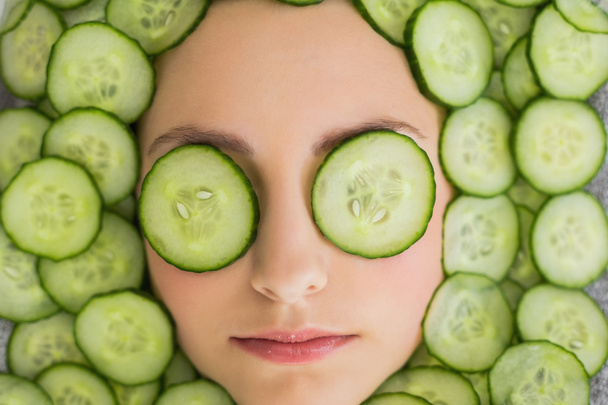 Beautiful woman with facial mask of cucumber slices on face - 写真・画像