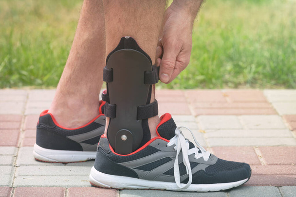 Man in athletic sneakers wearing ankle orthosis or brace - Фото, зображення