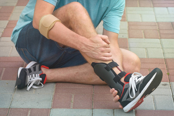 Mężczyzna w tenisówkach sportowych noszący ortezę lub ortezę na kostce - Zdjęcie, obraz