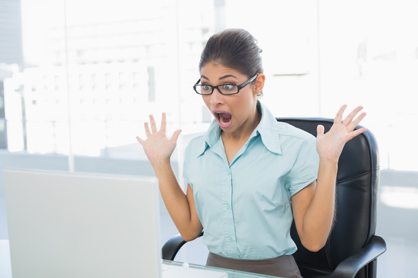 Shocked businesswoman looking at laptop in office - 写真・画像