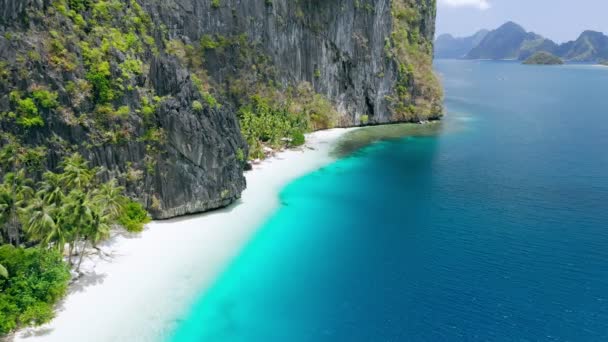 luchtfoto drone vliegen beelden van ongerepte tropische witte zandstrand omgeven door karst rotsachtige kliffen en turquoise zee pinagbuyutan eiland el nido palawan Filippijnen adembenemende bestemming - Video