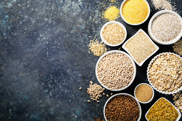 Selection of whole grains in white bowls - rice, oats, buckwheat, bulgur, porridge, barley, quinoa, amaranth - Foto, Bild