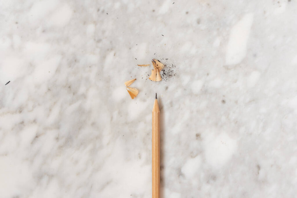 Izolovaná tužka právě ostříhaná a její hobliny na mramorovém pozadí, ploché ležely, horní pohled - Fotografie, Obrázek
