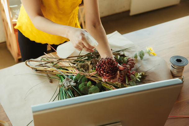 Fleuriste au travail : la femme montre comment faire un bouquet, travailler à la maison concept, gros plan
 - Photo, image