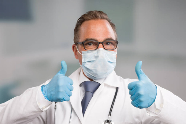 医療用フェイスマスクと医療用手袋の医者は両手で親指を上げて - 写真・画像