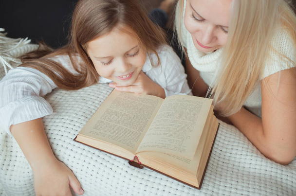 The family in the period of self-isolation reads books at home on the couch. How to keep yourself busy during quarantine without leaving your home - Фото, изображение