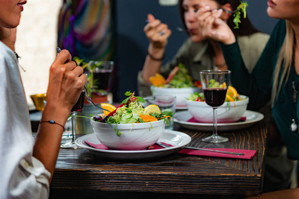 Restaurant végétarien. Amis féminines gaies appréciant la salade fraîche au restaurant et s'amusant
. - Photo, image
