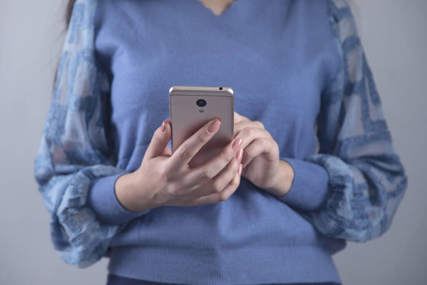 man hand holding smart phone on grey background - Foto, Bild