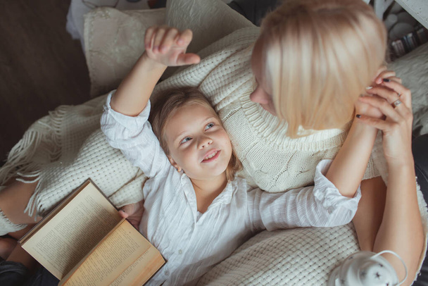 The family in the period of self-isolation reads books at home on the couch. How to keep yourself busy during quarantine without leaving your home - Foto, Imagen