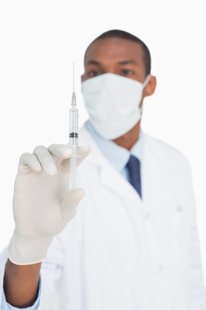 Médico varón con máscara y guante que sostiene una inyección
 - Foto, imagen