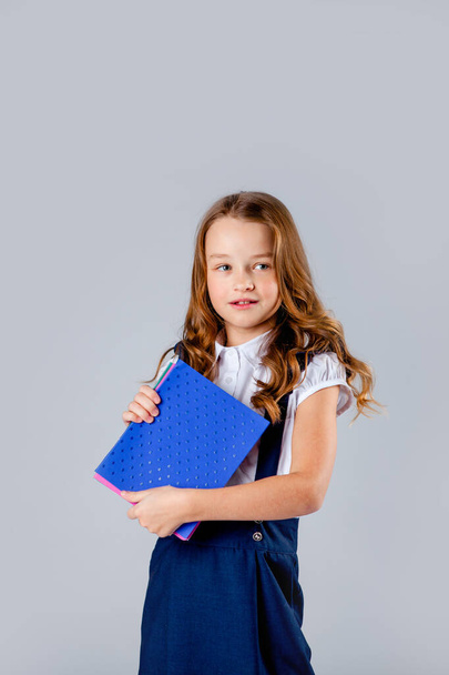 menina em uniforme escolar detém cadernos escolares em mãos
 - Foto, Imagem
