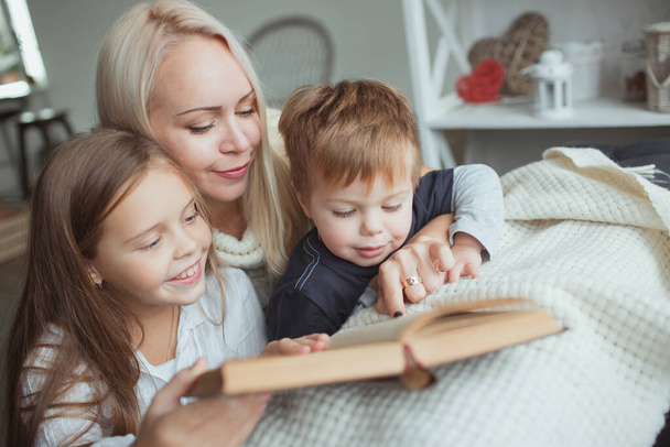 The family in the period of self-isolation reads books at home on the couch. How to keep yourself busy during quarantine without leaving your home - 写真・画像