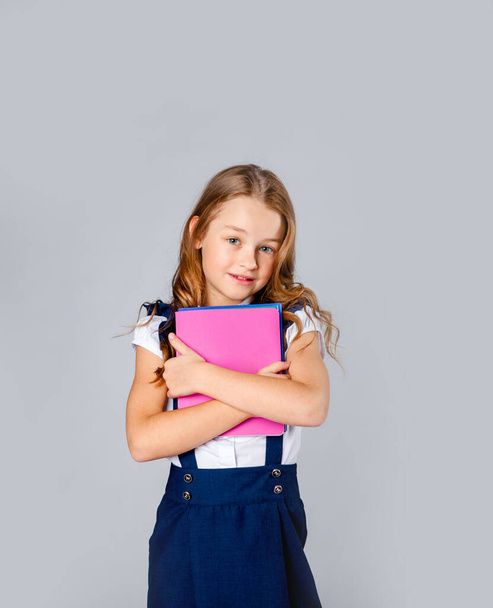 tyttö koulupuku omistaa koulun muistikirjat käsissä
 - Valokuva, kuva