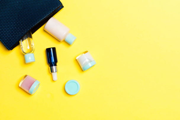 Γυναικεία τσάντα καλλυντικών με σετ προϊόντων ομορφιάς και κρέμας σώματος σε κίτρινο φόντο με χώρο αντιγραφής για το σχεδιασμό σας. - Φωτογραφία, εικόνα
