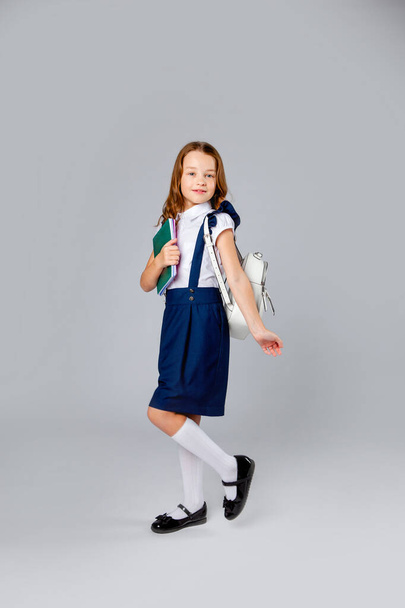 cute schoolgirl with a backpack holds notebooks - Photo, Image