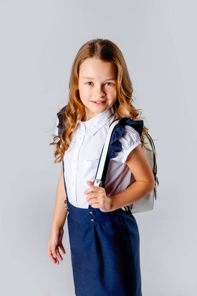 chica en uniforme escolar y con una mochila detrás
 - Foto, Imagen
