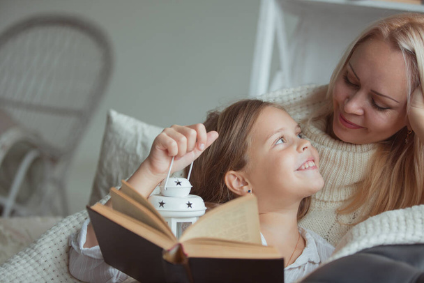 The family in the period of self-isolation reads books at home on the couch. How to keep yourself busy during quarantine without leaving your home - Foto, afbeelding