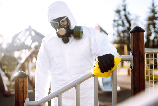 Hand of Man in protective suit washing and disinfection the playground, to preventing the spread of the epidemic of coronavirus, pandemic in quarantine city. Covid-19. - 写真・画像