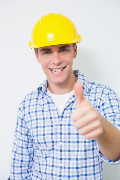Smiling handyman in yellow hard hat gesturing thumbs up - Photo, image