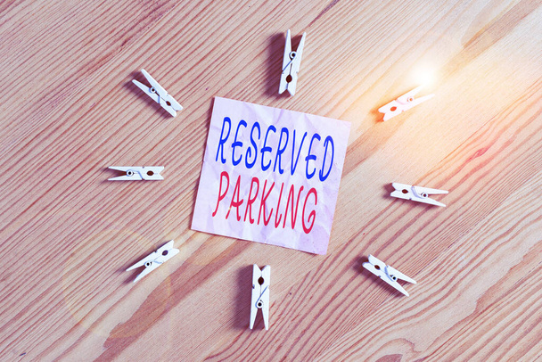 Writing note showing Reserved Parking. Business photo showcasing parking spaces that are reserved for specific individuals Colored clothespin papers empty reminder wooden floor background office. - Photo, Image