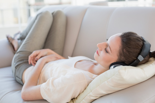 Relaxed casual young woman enjoying music on sofa - Foto, Imagem