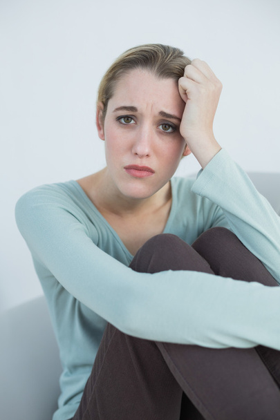 Natural young woman sitting worried on couch - Photo, image