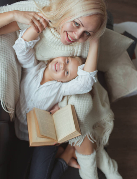 The family in the period of self-isolation reads books at home on the couch. How to keep yourself busy during quarantine without leaving your home - Foto, Imagem