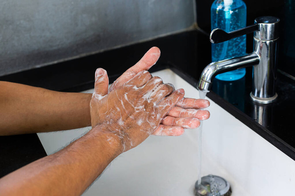 Чоловік миє руки в раковині, омолоджуючи вірус колони для санітарії та зменшуючи поширення COVID-19 по всьому світу, Гігієна, концепція санітарії
. - Фото, зображення
