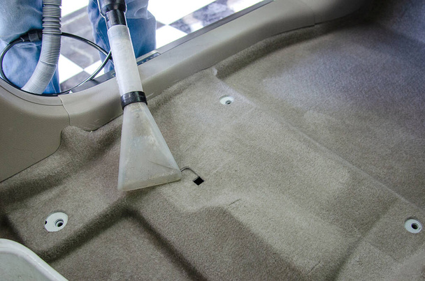 掃除機で車のカーペットをきれいにします。車の中で化学物質や汚れで細菌を殺す. - 写真・画像